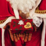 person wearing santa claus outfit while holding christmas gift