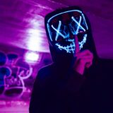 person wearing led mask doing silence gesture