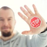 photography of a persons hand with stop signage