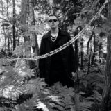 mysterious man in stylish clothes standing in forest