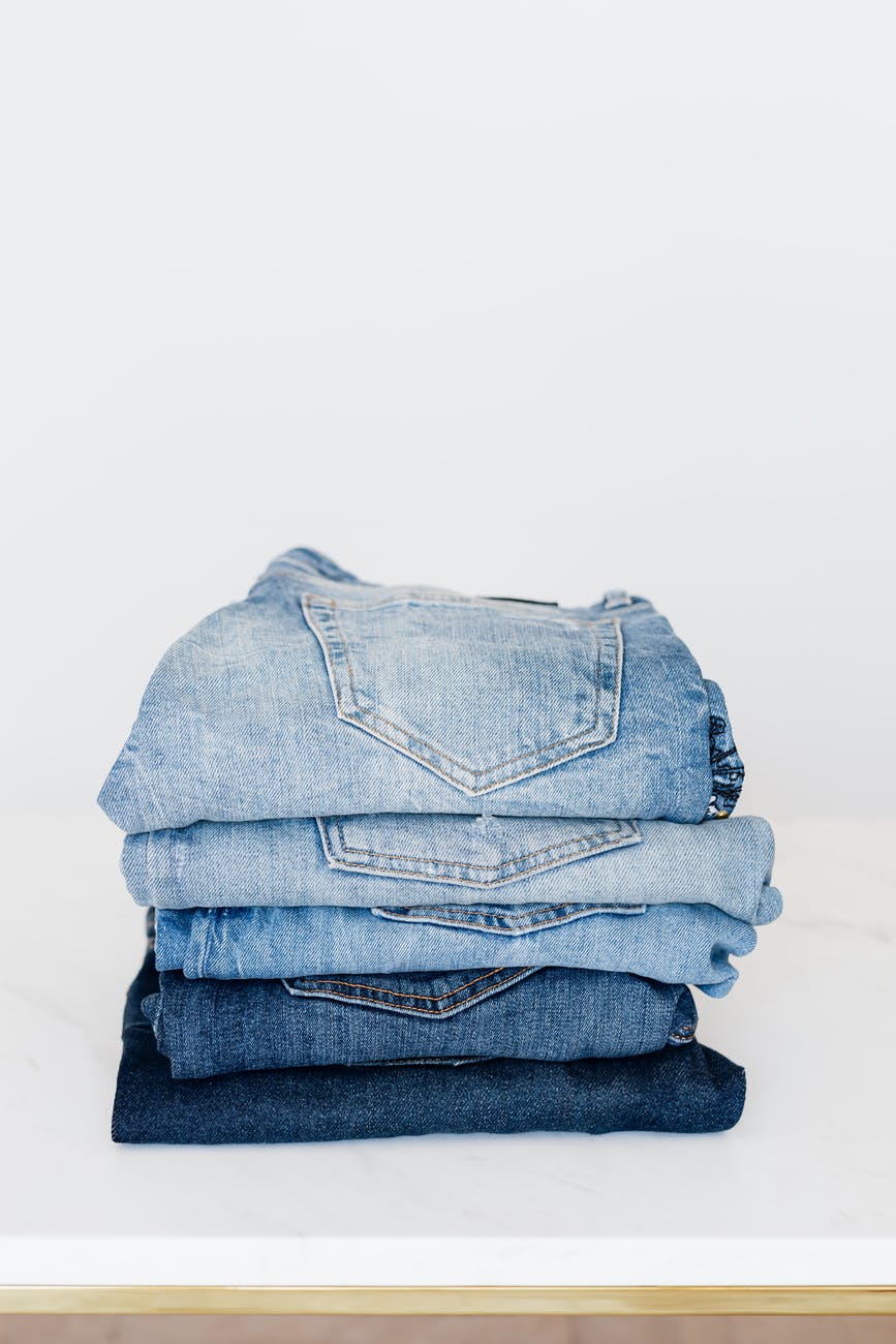 stack of jeans on white shelf
