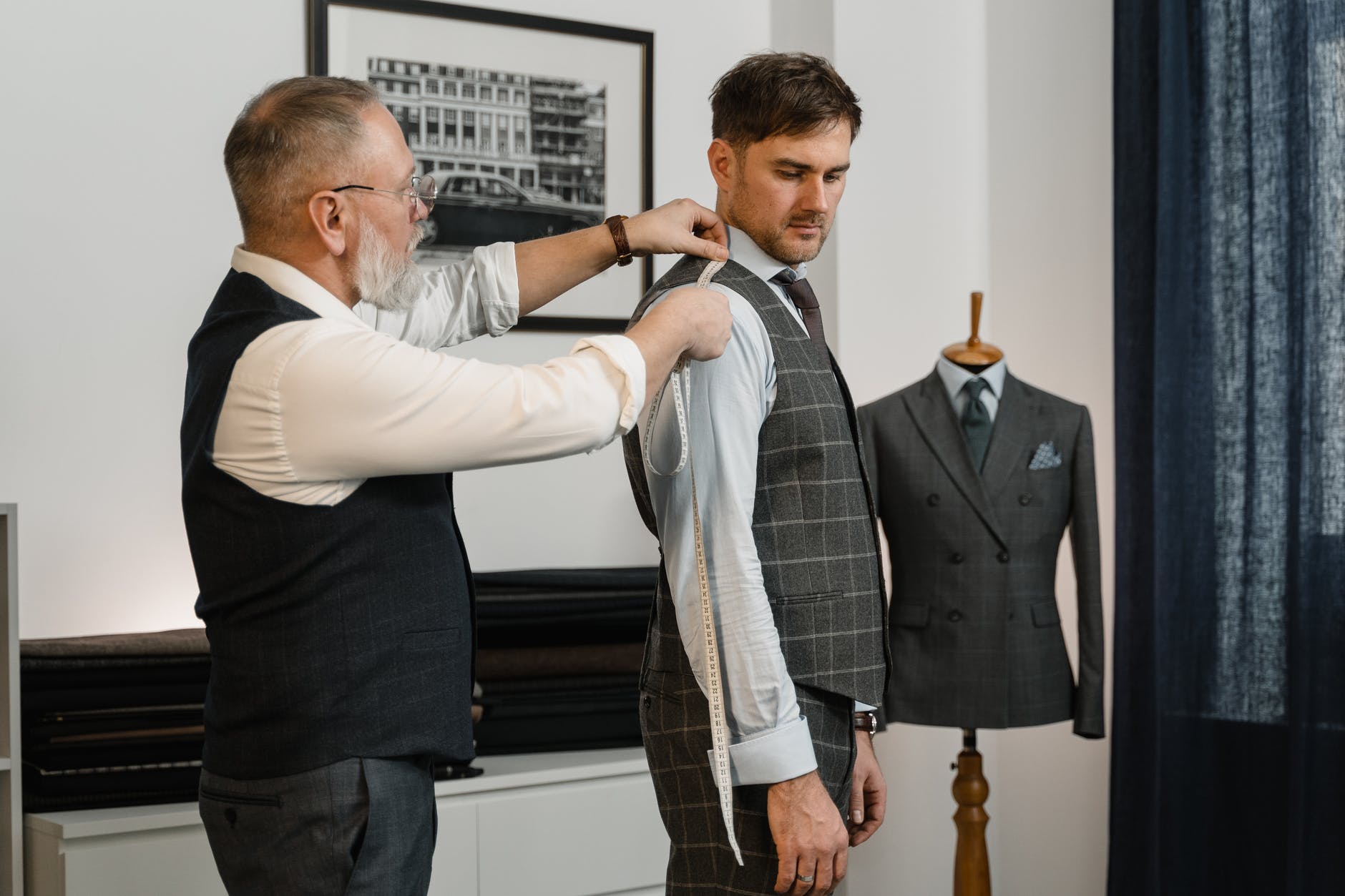 a tailor measuring his client using a tape measure