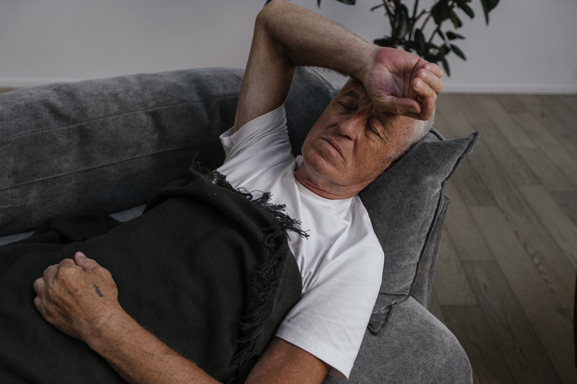 man in white shirt sleeping with hand on forehead