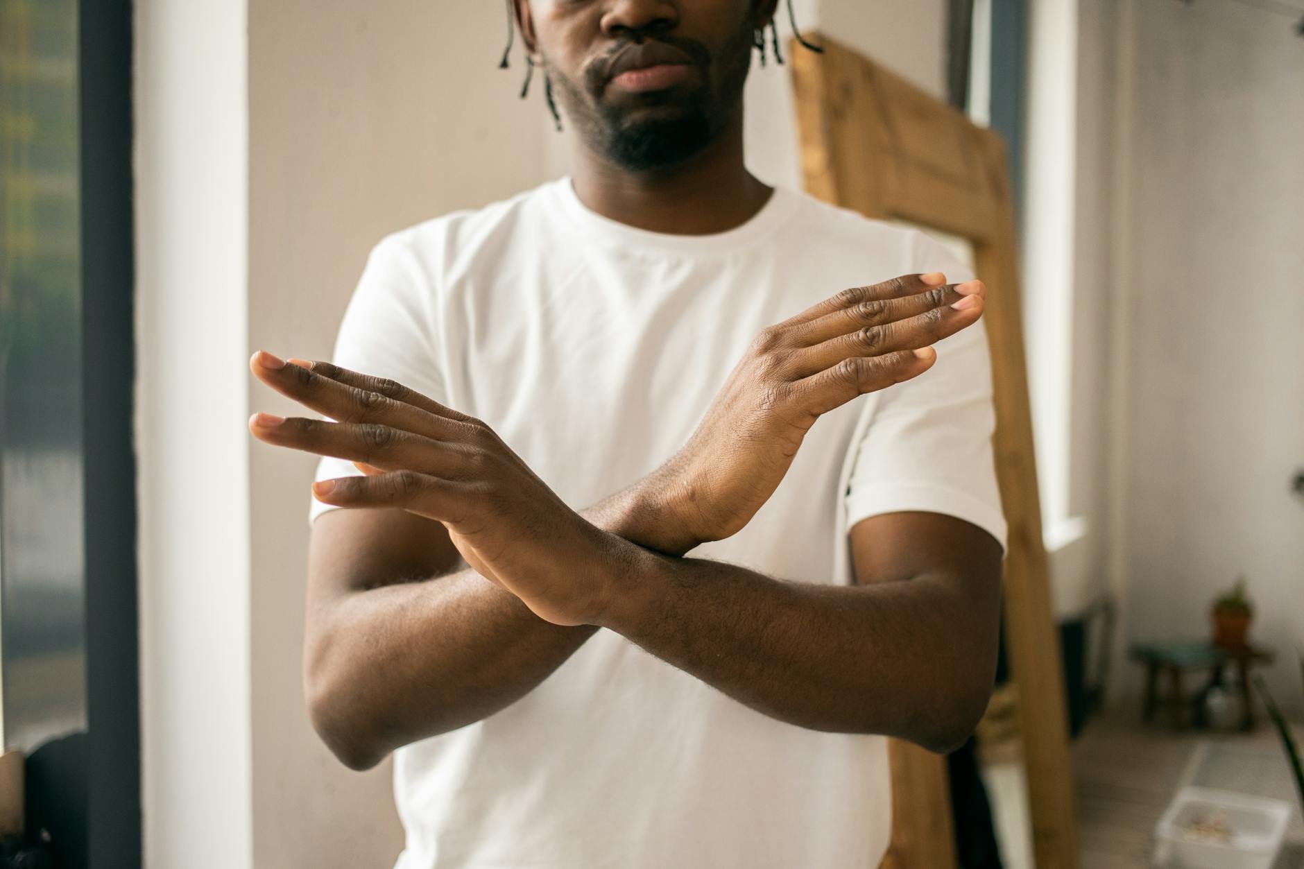 faceless black man showing stop gesture with crossed hands