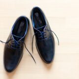 pair of black leather derby shoes placed on brown surface