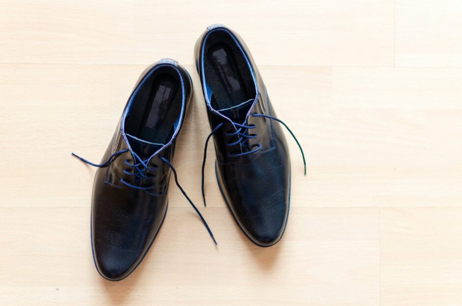 pair of black leather derby shoes placed on brown surface