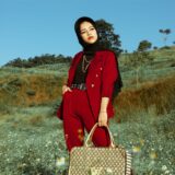 a woman in red blazer and pants holding a louis vuitton bag