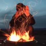 man sitting facing fire in pot during night