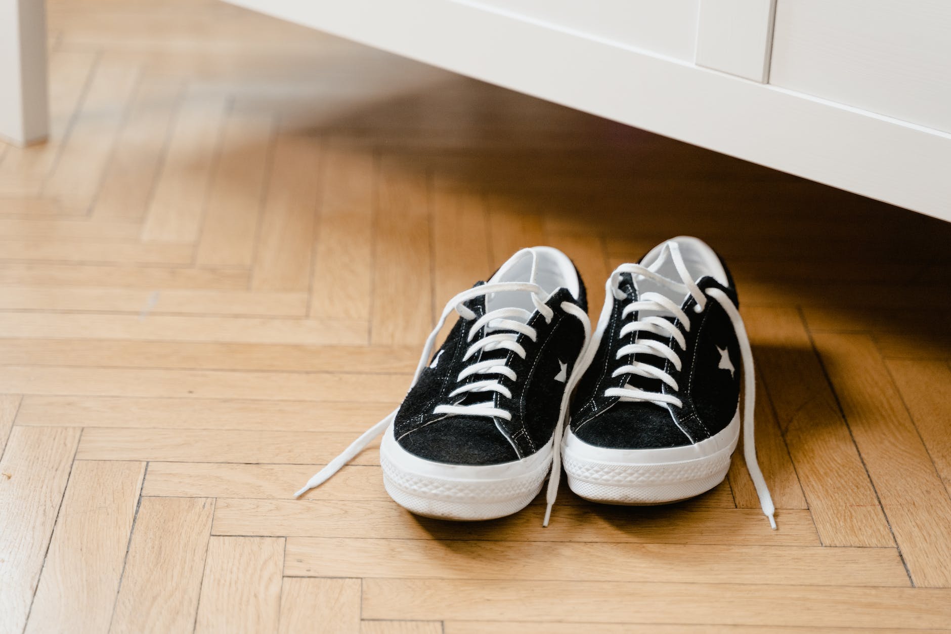 close up of a pair of black sneakers on a wooden floor
