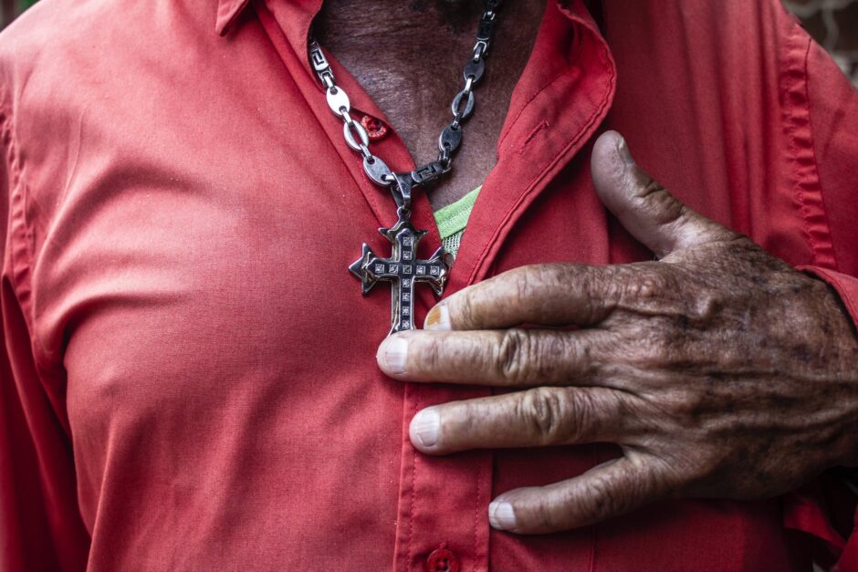 close up of old man showing silver cross on chest