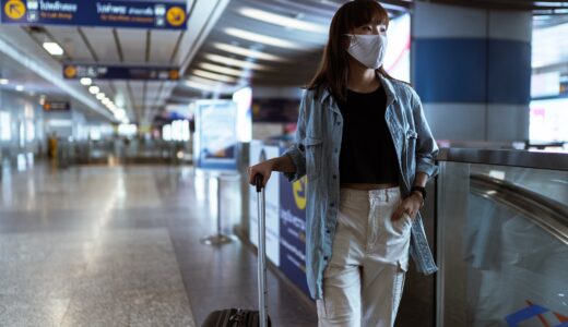 woman with a face mask holding her luggage