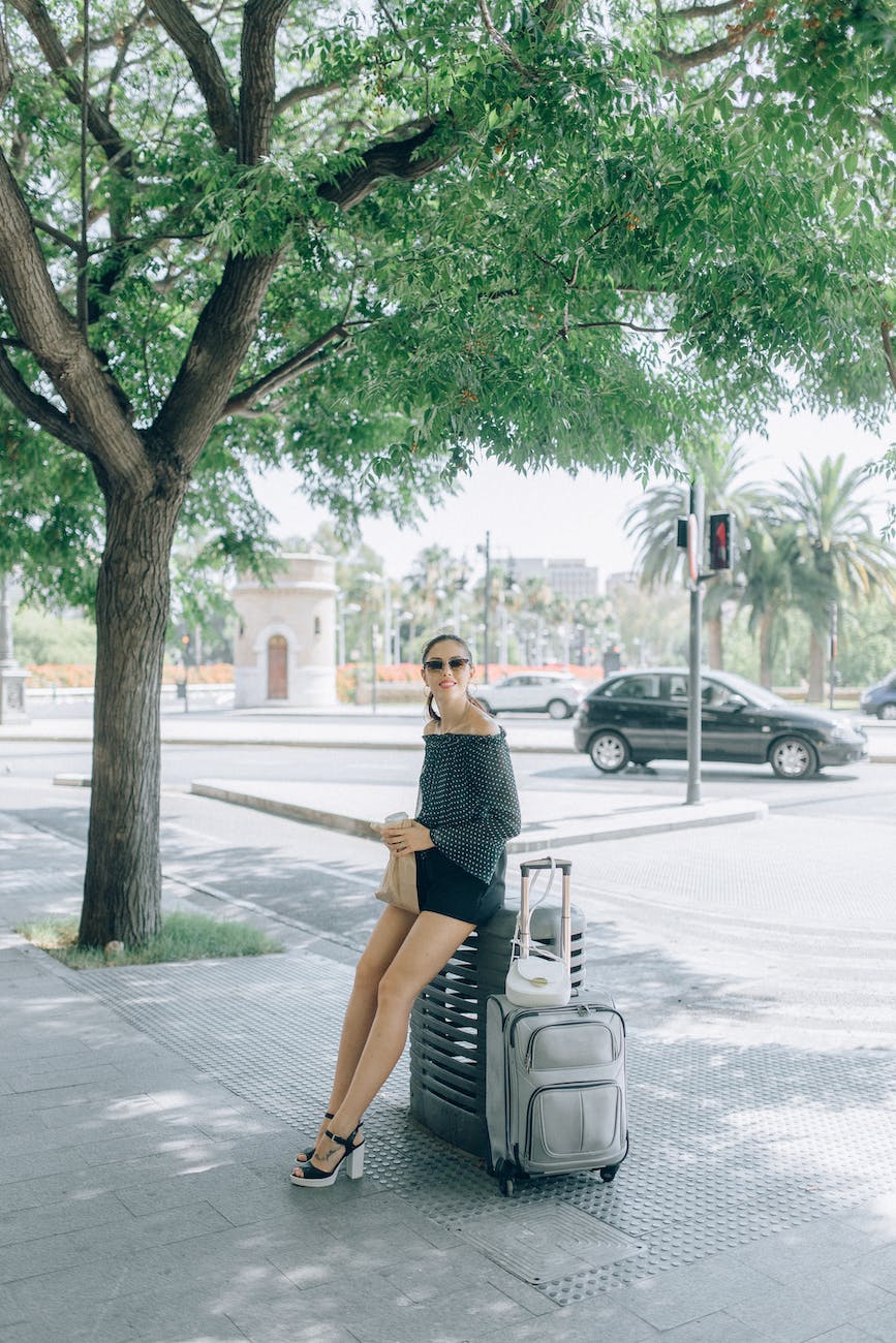 woman wearing sunglasses sitting on luggage