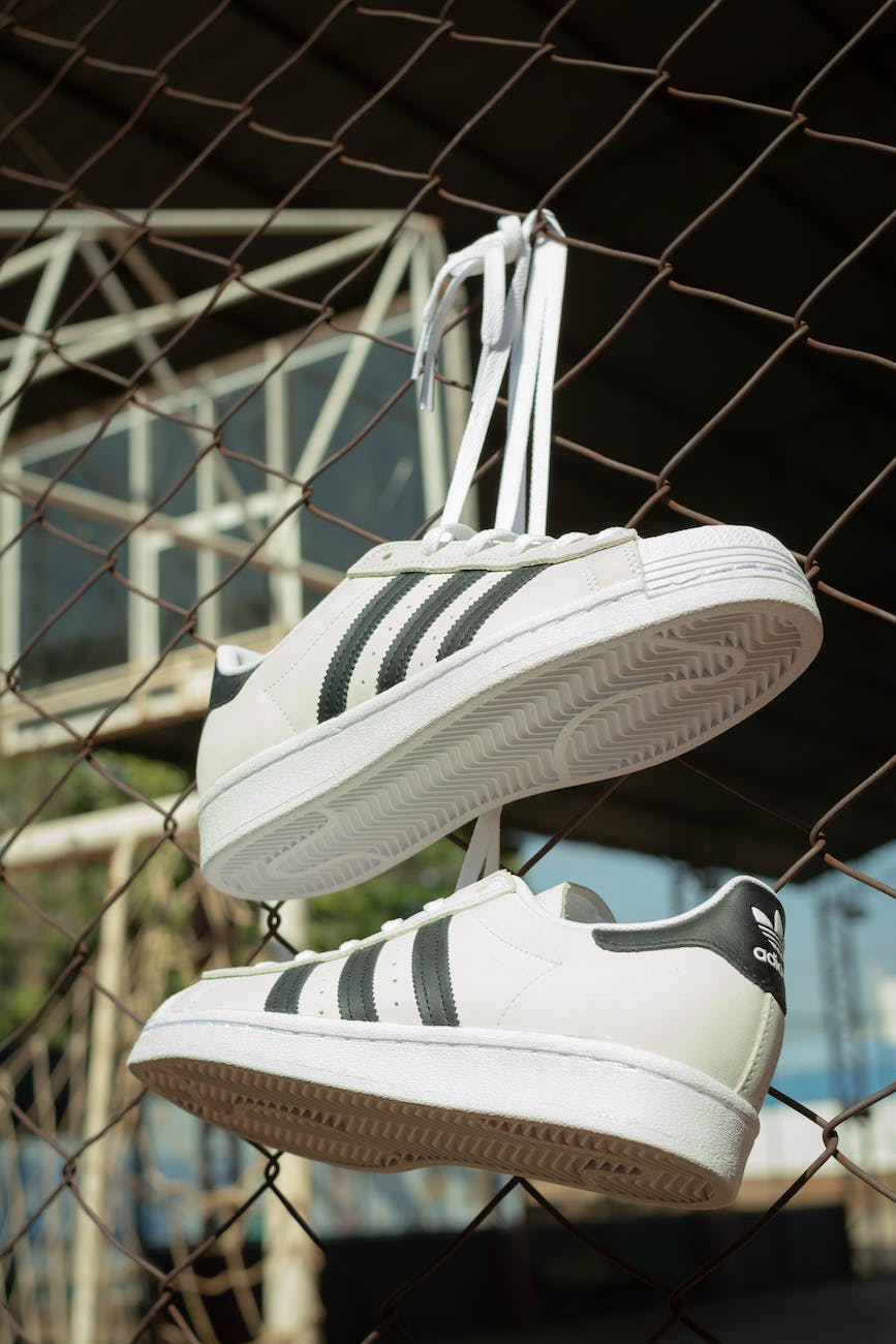 a stylish white sneakers hanging on a cyclone fence
