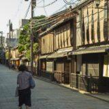 anonymous woman strolling on street near typical asian houses