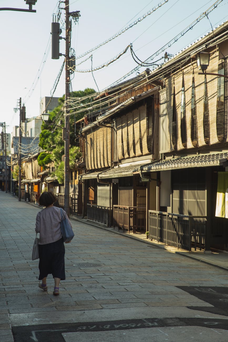 anonymous woman strolling on street near typical asian houses