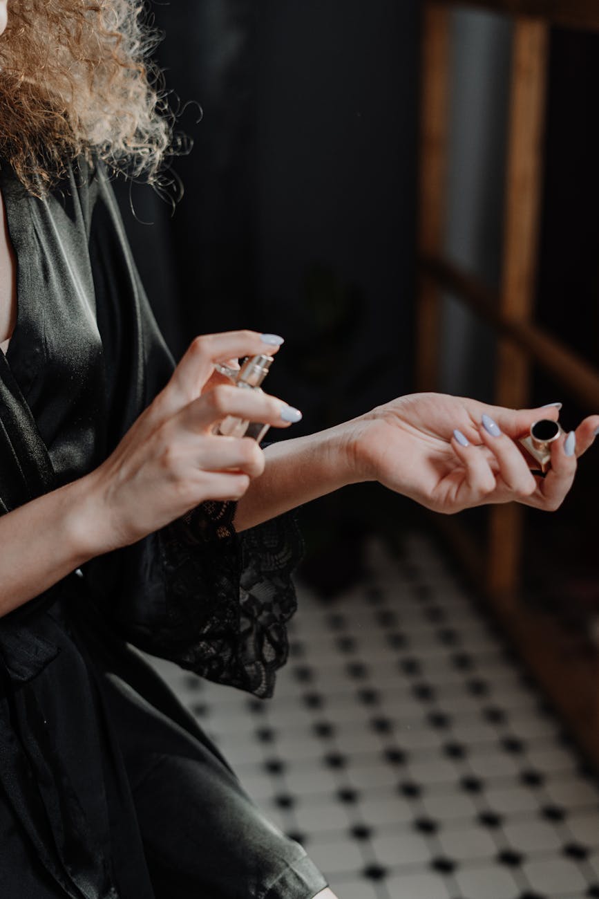 person in black silk robe spraying perfume