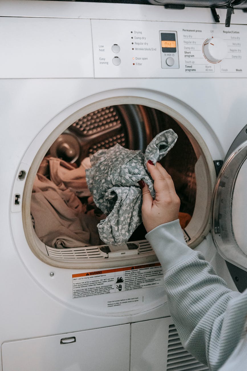 anonymous woman putting clothes in washing machine